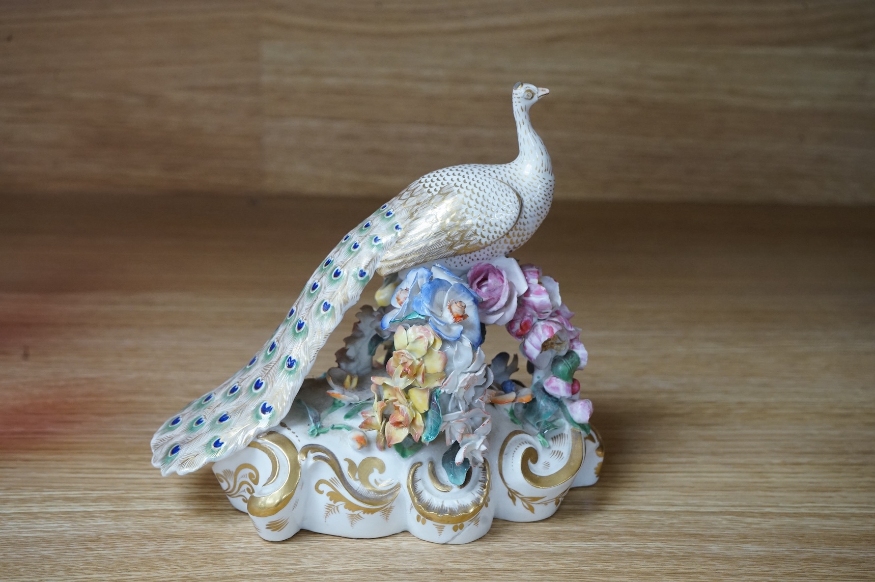 An ornate Bloor Derby peacock with floral encrusted decoration, 16cm high